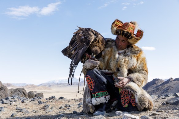 A Kazak Mongolian eagle hunter with his eagle perched on his right arm.